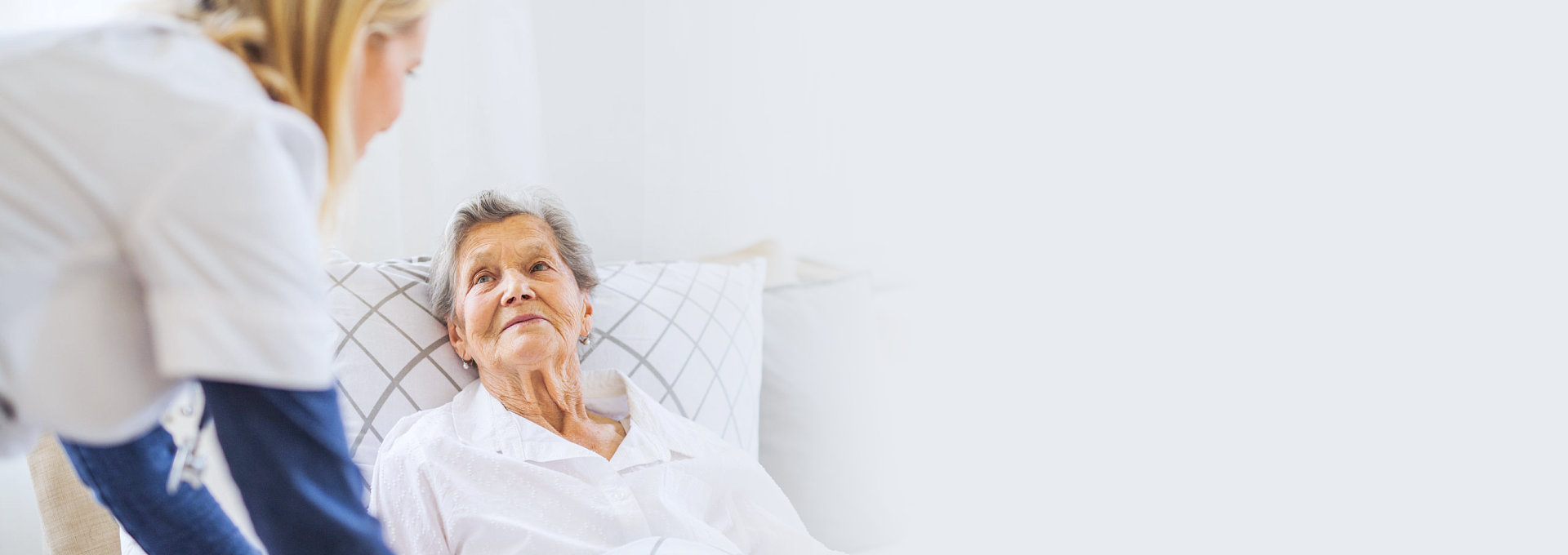 comfortable senior woman on bed talking to her caregiver