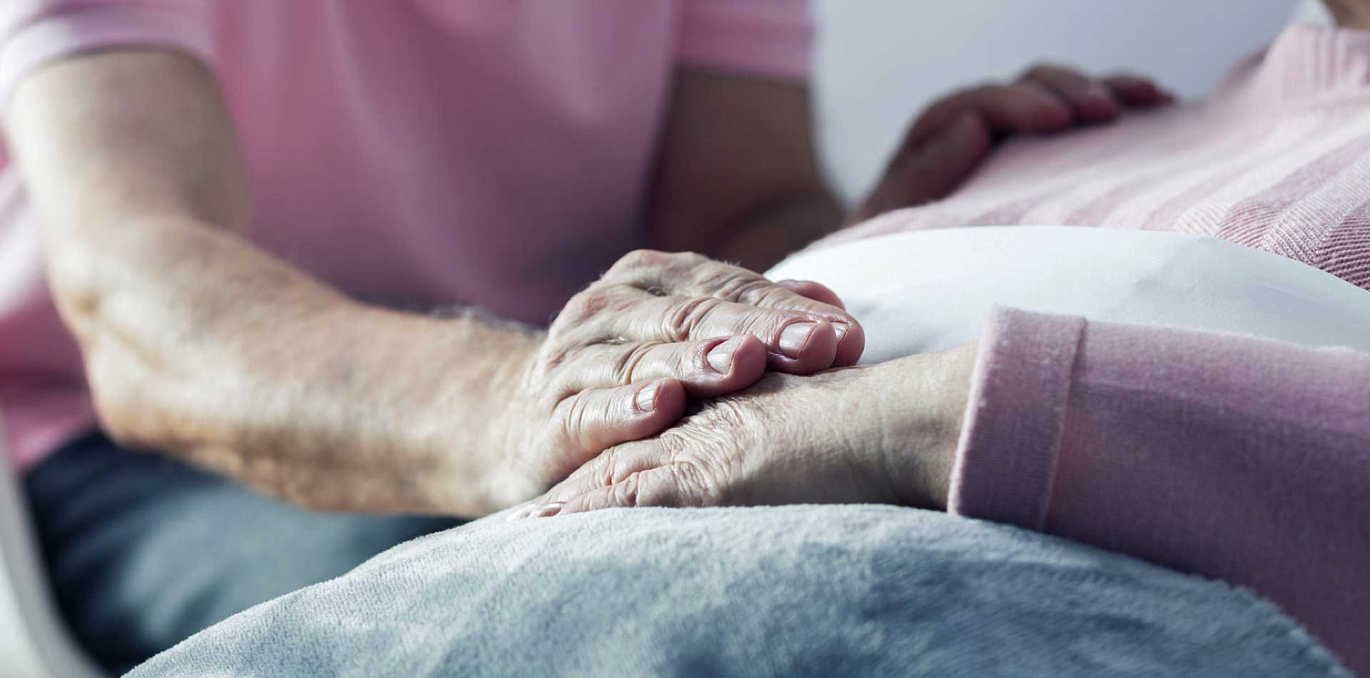 caregiver holding senior woman's hand